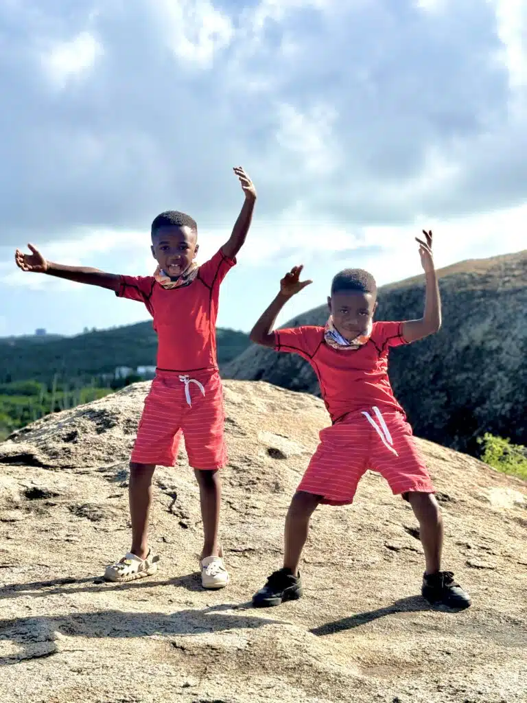 my twin boys dressed in red on top of a rock formation at Ayo Rock Formation in Aruba